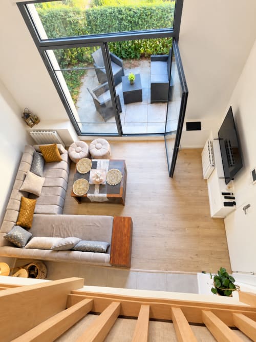 Salón moderno en el apartamento La Perle du Léman en Douvaine con tragaluces, sofá beige y vistas a la terraza del jardín
