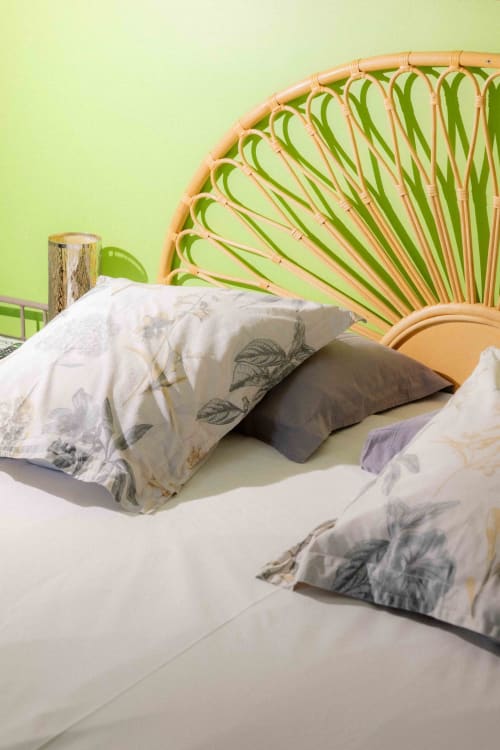 Cozy bed with floral pillows and woven rattan headboard at Moulin de Gaubourg, Anjou B&B