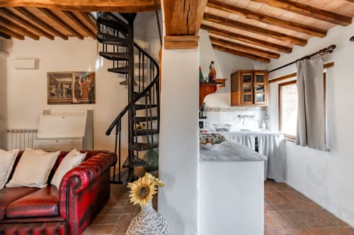 Accogliente appartamento rustico con divano in pelle rossa, scala a chiocciola, travi in legno e cucina a vista presso l'hotel Quarantallina