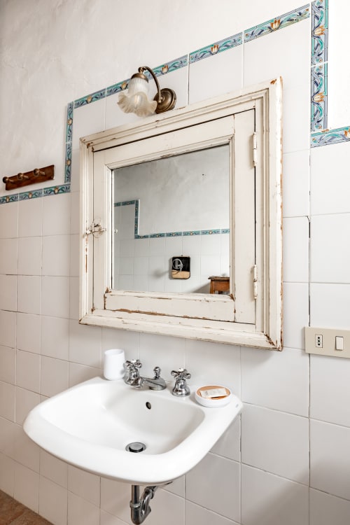 Lavabo vintage con bordo di piastrelle decorative e specchio incorniciato presso l'hotel Quarantallina a Buonconvento, Italia
