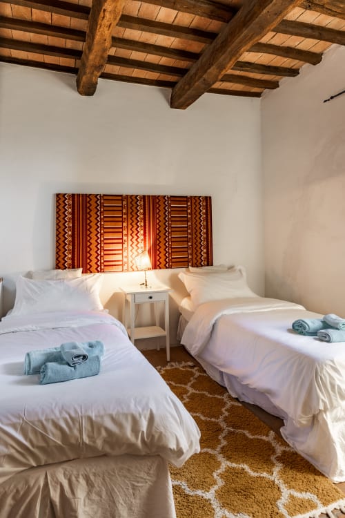 Letti gemelli con biancheria bianca e asciugamani piegati nella camera Appaloosa dell'hotel Quarantallina a Buonconvento, con arredamento in legno