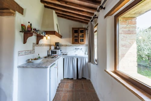 Cucina rustica nell'appartamento Appaloosa dell'hotel Quarantallina a Buonconvento, con banconi in marmo e vista sul giardino