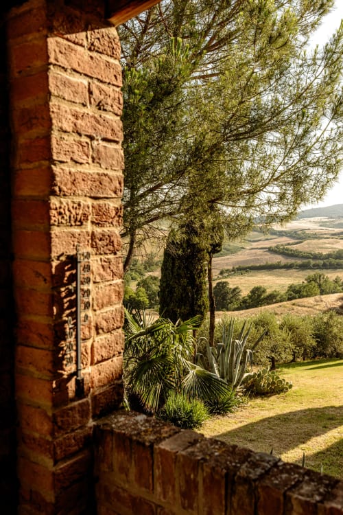 Vista della campagna toscana dall'hotel Quarantallina a Buonconvento, attraverso l'architettura rustica in mattoni con cipressi