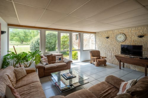 Spacieux séjour du gîte Virginie au Domaine Des Escouanes avec vue sur le jardin, foyer en pierre et confort