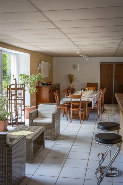 Spacieux séjour et salle à manger du gîte Domaine Des Escouanes avec table dressée, sièges en osier et vue sur le jardin
