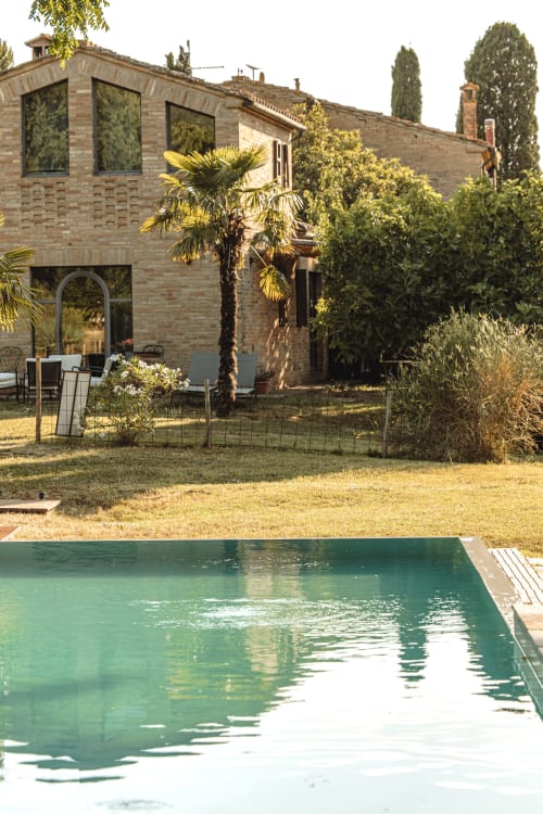 Moderno hotel in mattoni con piscina e giardino a Buonconvento, Italia con palme e architettura contemporanea