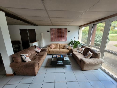 Spacieux salon du cottage Virginie au Domaine Des Escouanes avec canapés marron, TV écran plat et vue sur le jardin