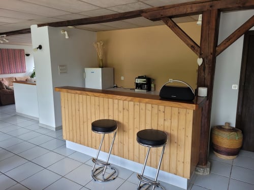 Réception du gîte avec comptoir en bois, tabourets de bar et équipements d'accueil au Domaine Des Escouanes à Prudhomat