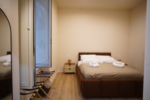 Camera San Severo dell'hotel Domusè Napoli con letto in legno, biancheria bianca, accesso al balcone e comfort moderni