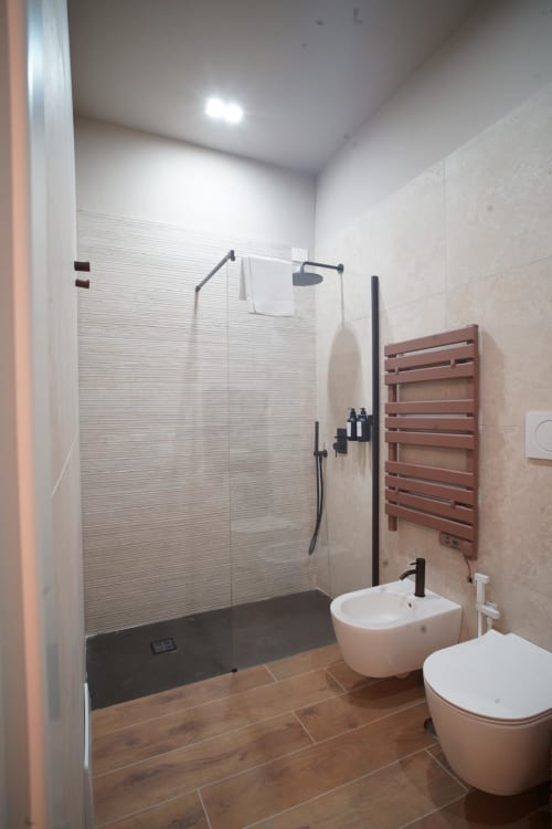 Bagno moderno nella suite San Severo dell'hotel Domusè Napoli, con doccia walk-in, toilet, bidet e scaldasalviette elettrico