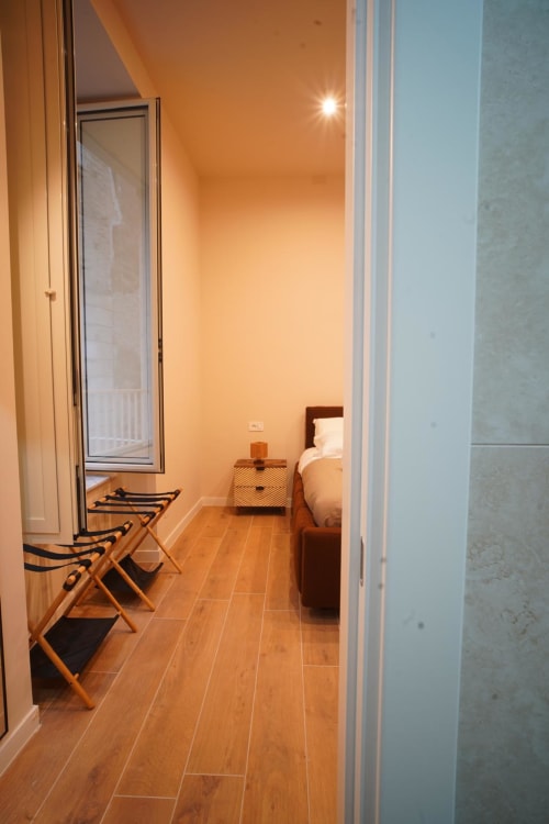 Stanza San Severo a Domusè Napoli con pavimento in legno, portabagagli, letto, comodino e finestra