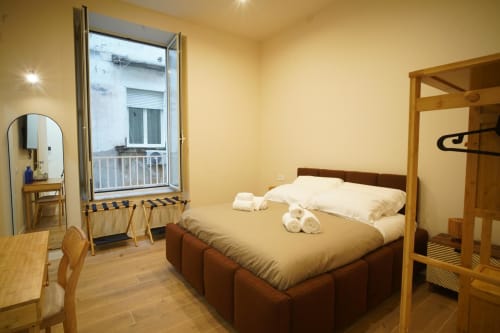 Camera San Severo dell'hotel Domusè a Napoli con letto in legno, specchio, porta-balcone e illuminazione calda