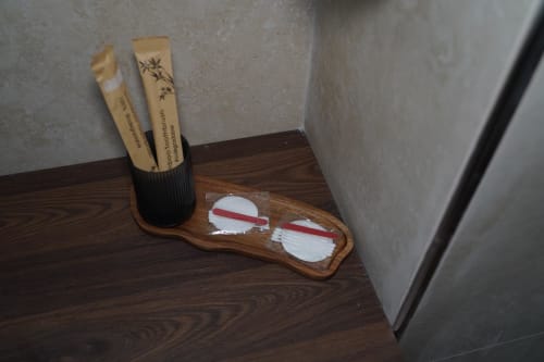 Vassoio di cortesia in legno con spazzolini di bambù e articoli da toilette nella camera San Severo dell'hotel Domusè, Napoli
