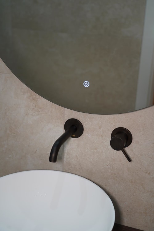 Bagno moderno nella stanza Domusè San Severo a Napoli con rubinetto nero minimalista e specchio rotondo