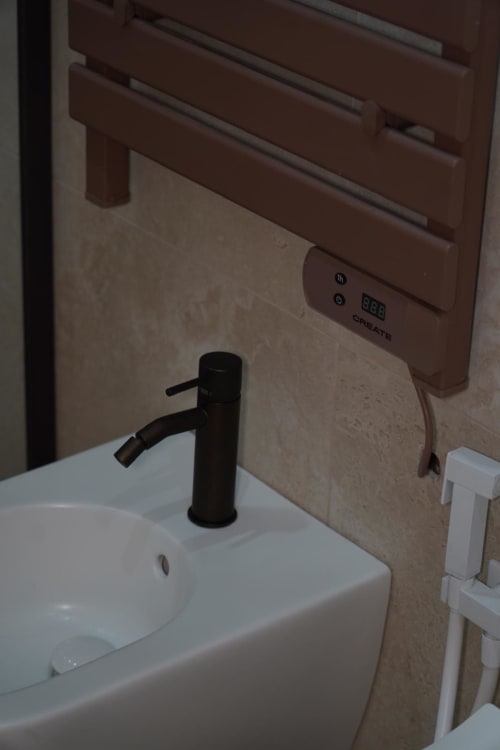 Lavabo moderno con rubinetto nero e dispenser di asciugamani a parete presso l'hotel Domusè di Napoli