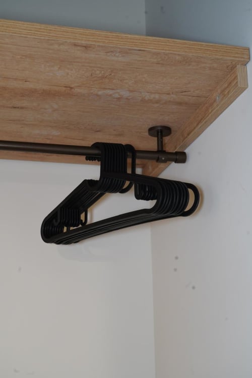 Appendiabiti neri su asta metallica sotto la mensola in legno nella suite Capodimonte dell'hotel Domusè a Napoli