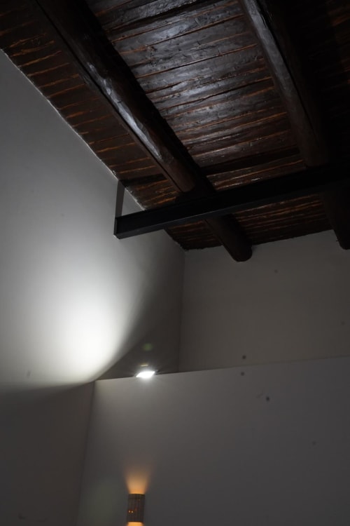 Travi a vista in legno scuro nella camera Capodimonte dell'hotel Domusè a Napoli