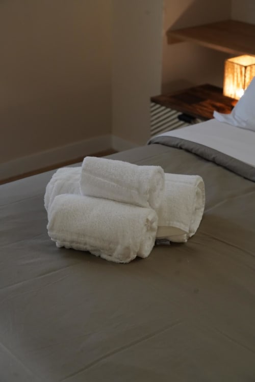 Asciugamani bianchi arrotolati disposti sul letto della camera Capodimonte all'hotel Domusè di Napoli