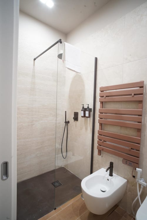 Bagno moderno all'hotel Domusè di Napoli con doccia walk-in, lavabo bianco, scaldasalviette e design minimalista