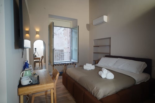 Camera Capodimonte dell'hotel Domusè a Napoli con letto, asciugamani, scrivania, specchio e vista sul balcone