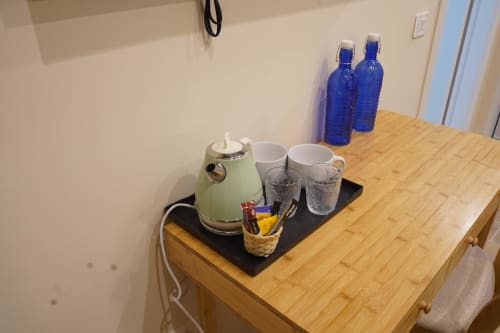 Stazione di benvenuto della sala Capodimonte presso Domusè Napoli con bollitore, tazze, bicchieri e bottiglie d'acqua blu su tavolo in legno