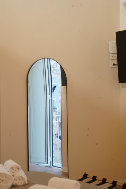 Specchio ad arco alto nella camera San Gennaro dell'hotel Domusè a Napoli, che riflette la finestra con vista sulla città
