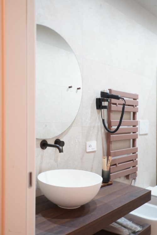 Lavabo moderno con bacinella bianca e specchio rotondo presso l'hotel Domusè a Napoli