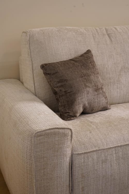 Poltrona rivestita in beige con cuscino grigio scuro nella suite San Gennaro dell'Hotel Domusè a Napoli
