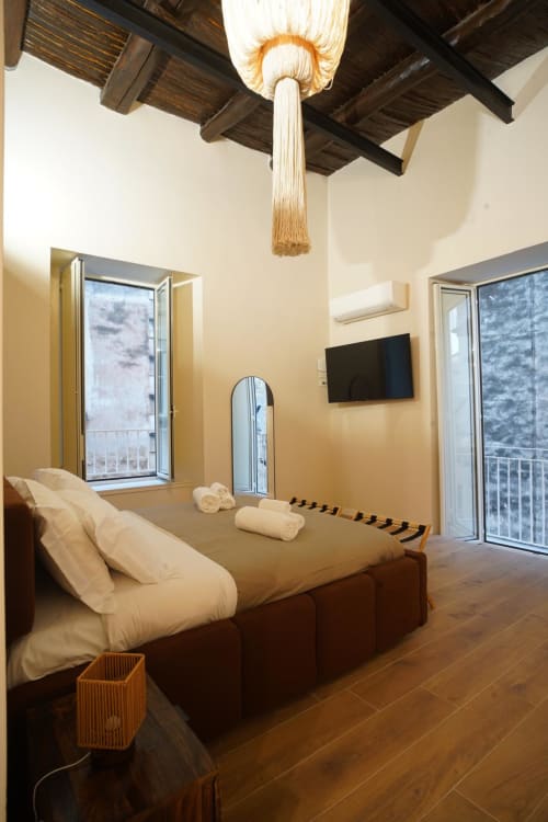 Camera San Gennaro presso Domusè Napoli con soffitto a travi, letto, balconata e TV schermo piatto