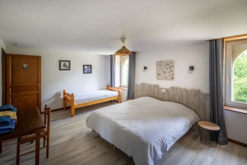 Spacieuse chambre du Domaine Des Escouanes avec lit double, lit simple, mobilier en bois et vue sur le jardin