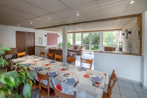 Salle à manger du Domaine Des Escouanes avec tables dressées, chaises en bois et vue sur le salon à Prudhomat