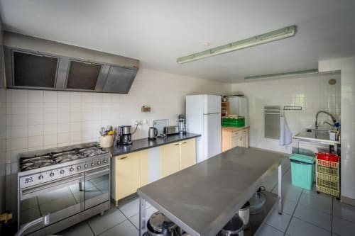 Cuisine spacieuse du gîte Domaine Des Escouanes avec électroménagers en acier inoxydable, armoires crème et îlot central