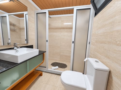 Modern bathroom at Casa do Moinho villa in Madeira with dual toilets, vessel sink, walk-in shower, and beige tile finishes
