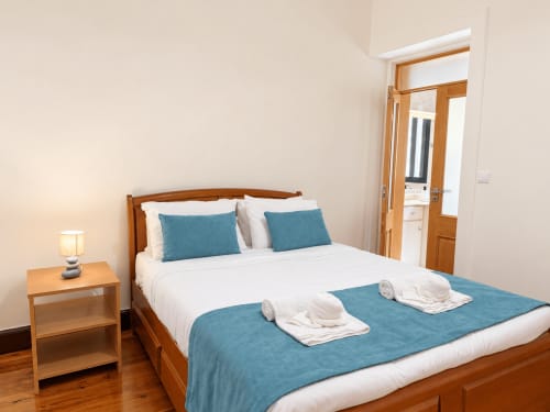 Bright bedroom at Casa do Moinho villa in Ribeira Brava with wooden bed, teal accents, and wooden nightstand