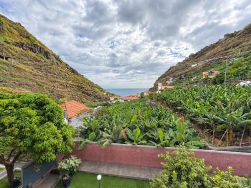 Villa Casa do Moinho in Ribeira Brava with sea view, banana plants, and coastal valley landscape under cloudy sky