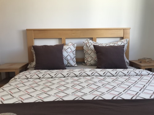 Tassila apartment bedroom with wooden headboard, patterned bedding, and black pillows at Imsouane Surf Paradise