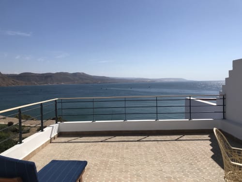 Oceanfront terrace at Imsouane Surf Paradise with sea views, loungers, and railing overlooking Moroccan coastline