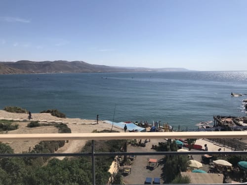 Imsouane beach view from Tassila apartment with golden sand, blue ocean, fishing boats, and coastal mountains in Agadir,