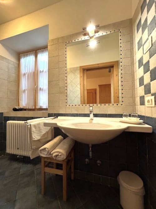 Modernes Badezimmer im Residenza B&B Sissi mit Aufsatzwaschbecken, großem Spiegel und karierten Kacheln in Almazzago