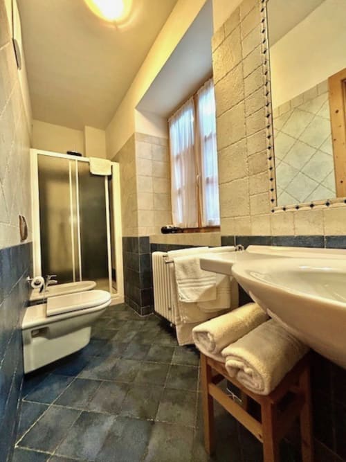 Geräumiges Badezimmer in der Residenza B&B Sissi in Almazzago mit Badewanne, Dusche, Toilette und cremefarbenen Handtüchern