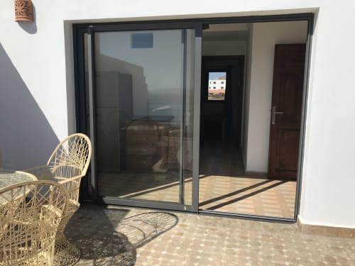 Tassila apartment terrace at Imsouane Surf Paradise with sea views, modern sliding glass doors, and wicker seating