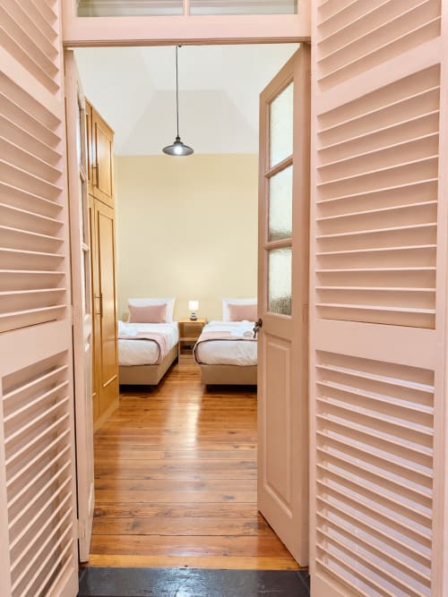 Modern bedroom at Check Madeira villa with twin beds, wooden floors, and pink louvered doors in Ribeira Brava