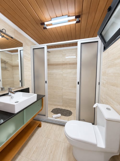 Modern bathroom at Check Madeira hotel in Ribeira Brava with wooden ceiling, vessel sink, toilet, and walk-in shower