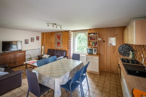 Séjour ouvert à Domaine Des Escouanes avec salle à manger, sièges en cuir, cuisine et murs lambrissés