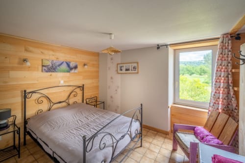 Chambre cosy du Domaine des Escouanes avec lambris, lit ornementé et vue sur la campagne à Prudhomat