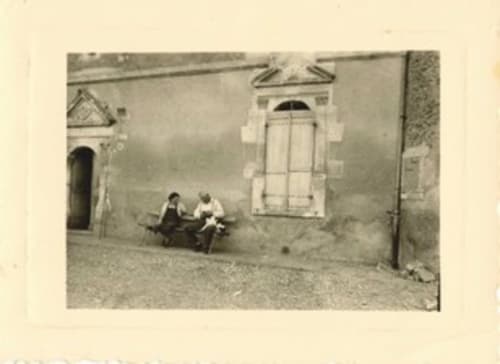 Deux invités se détendent devant la façade en pierre rustique du Château de Ribourdin à Chevannes, France, avec ses fenêtres en arche