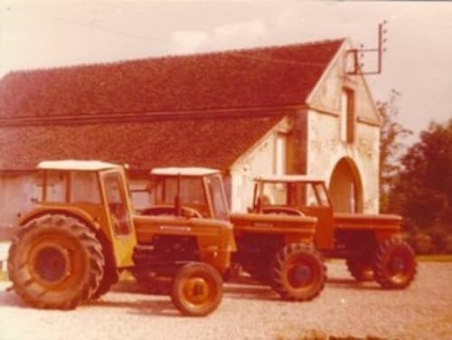 Tracteurs rouges garés près d'une maison de campagne au toit rouge au Château de Ribourdin, un gîte de charme à Chevannes,