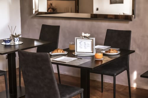 Area colazione moderna a Corte Livia con tavolo nero, cornetti, laptop e succo d'arancia a Forlì
