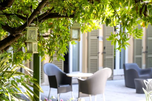Cortile di Corte Livia con lanterne sospese, verdure lussureggianti e accogliente zona lounge a Forlì
