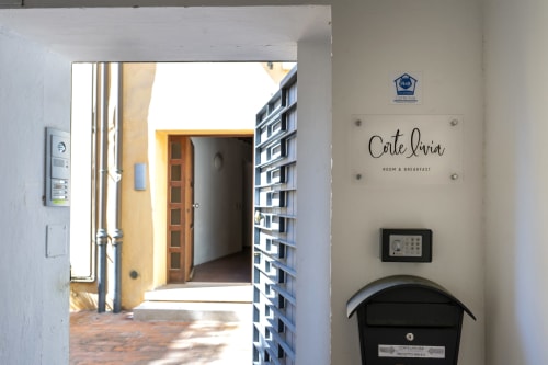 Ingresso della Corte Livia B&B a Forlì con porta gialla, citofono e cassetta postale su muro bianco